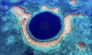 dark blue hole amid islands in shallow ocean